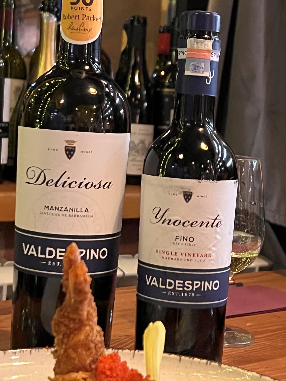 Două sticle de sherry Valdespino pe masă, lângă farfurie